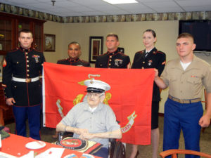 Marines from MCB Quantico hold a USMC flag while standing behind retired Master Gunnery Sgt. John H. Deters