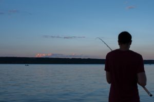 A man fishes at dawn.